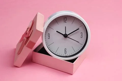 Clock in a gift box on a pink background. Stockfoto's
