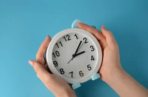 Clock in hands on a blue background. Stock Photos