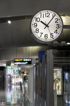 The clock hang over a empty corridor in the airport. Stock Photos