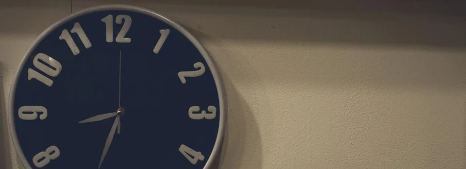 Clock hanging on the wall in the darkness. Stock Photos