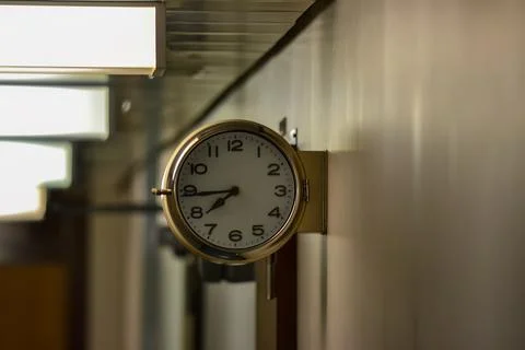 A clock hanging on a wall with the hands at the numbers 7 and 9 Stock Photos