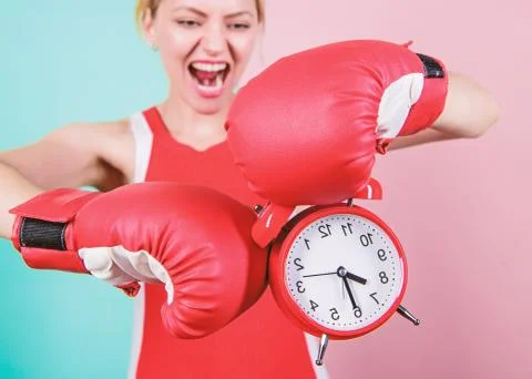The clock keeps incorrect time. Emotional woman holding clock in boxing gloves Stock Photos