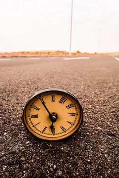 A clock is laying on the ground with the hands at the numbers 3 and 9 Foto stock