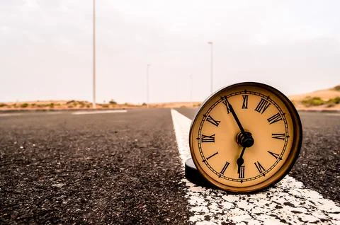 A clock is laying on the road, with the hands pointing to the numbers 1 and 9 Stockfoto's
