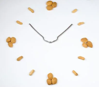 Clock made with almonds, peanuts and a nutcracker Stock Photos