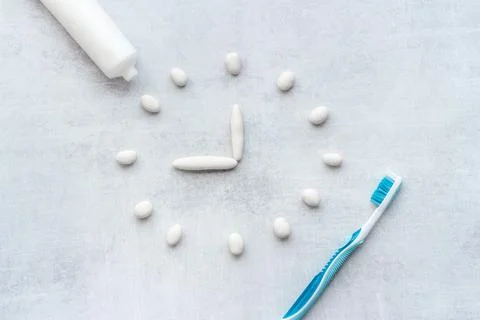 Clock made of toothpaste with toothbrushes. Oral care and dental hygiene concept Stock Photos