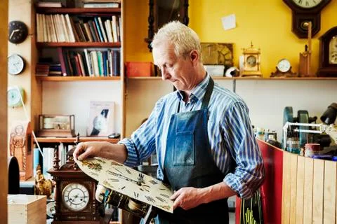 A clock maker viewing his work in the workshop. Stock Photos