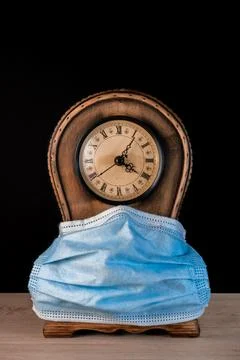 Clock with mask on black background Foto stock