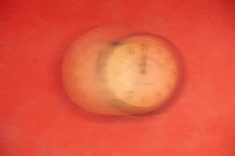 The clock is out of focus on a red background. Running time. Stock Photos