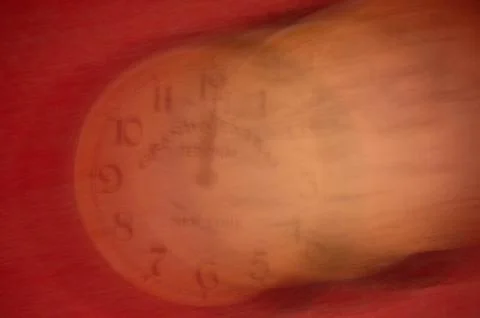 The clock is out of focus on a red background. Running time. Stock Photos