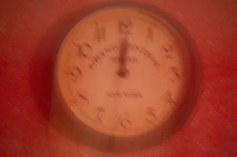 The clock is out of focus on a red background. Running time. Stock Photos