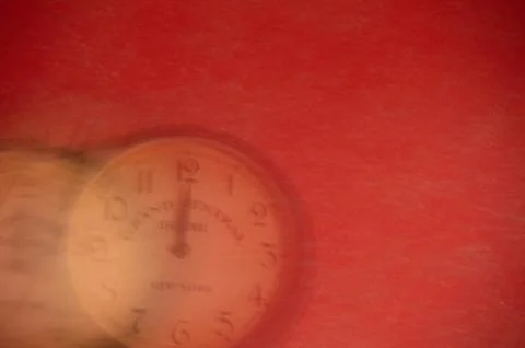 The clock is out of focus on a red background. Running time. Stock Photos