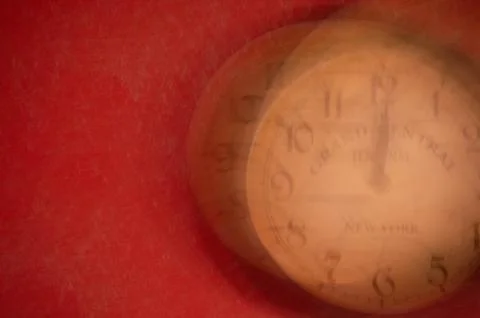 The clock is out of focus on a red background. Running time. Stock Photos