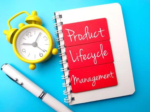 Clock, pen, and notebook written with text Product Lifecycle Management on blue 스톡 사진