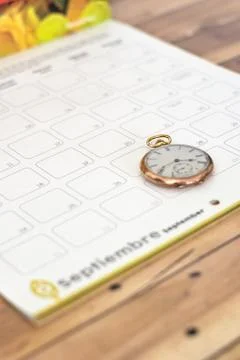 Clock on a planner on a wooden table - time management concept Foto stock