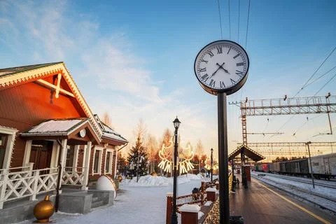 A clock on a post in front of a building with a snowy landscape Stock Photos