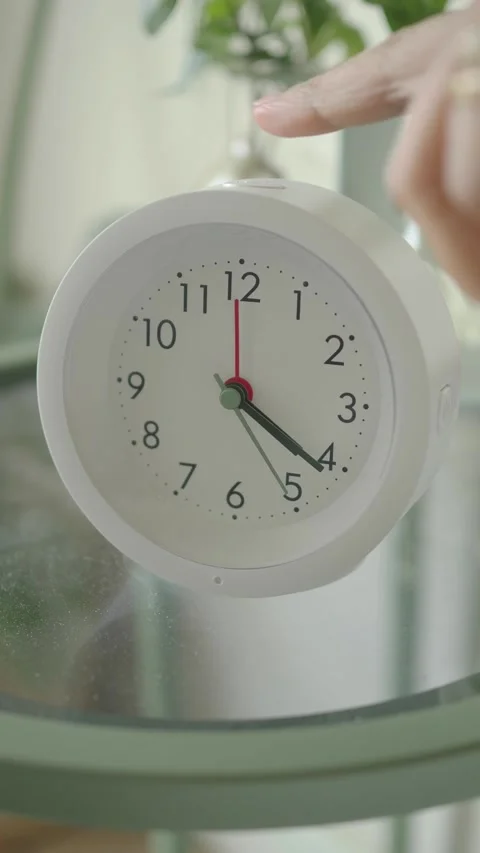 Clock showing time on a table with green plants around Stock Footage 339315039