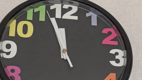 Clock shows time changes using a colorful design on a simple wall Stock Footage 341619585