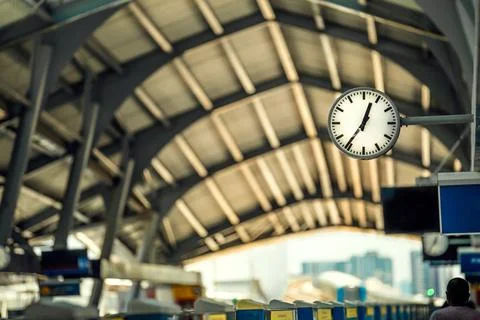 Clock at sky train terminal platform screen in the back and train is coming Stock Photos