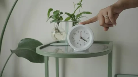 Clock on table with plants in simple room setting Stock Footage 335432335