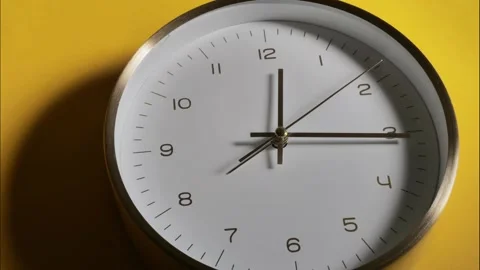 The clock is ticking very fast. A wall clock on a yellow background rotates Video stock 221123821