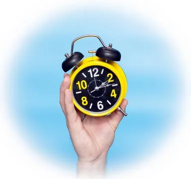 Clock time concept. Alarm clock in a man's hand on a blue background on the.. Stock Photos