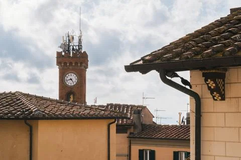 Clock tower above tiled rooftops in Tuscan village Photos