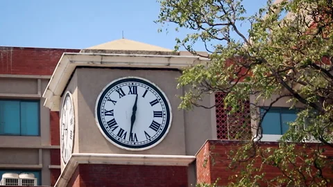 Clock tower on academic building under clear sky in India Vídeos de archivo 332613248