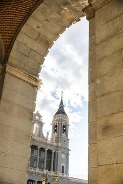 A clock tower building is viewed through a stone archway Stock Photos