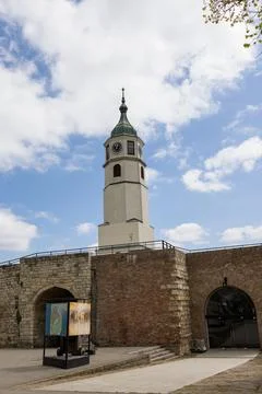 A clock tower captured under a bright blue sky with scattered clouds. Stock Photos