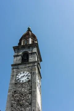 Clock tower of Chiesa Parrocchiale dei Santi Pietro e Paolo at center square in Stock Photos