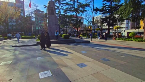 A clock tower in a city square with people walking around Stock Footage 273009756