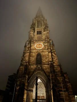 Clock tower of the Freiburg Minster on a cold, foggy winter night Foto stock