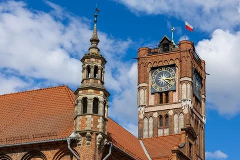 Clock tower of the Old Town Hall in Torun rises above red brick facades. Photos
