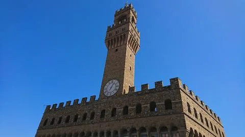 The clock tower of Palazzo Vecchio stands majestically against a clear blue sky Stock Photos