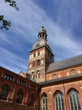 Clock tower rises above old brick building under blue sky with clouds durin.. Stock Photos