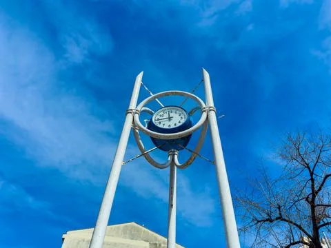 A clock tower shows the time on its large face. The tower is metal and positi Stock Photos