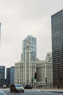 Clock tower stands between modern buildings in Chicago under a cloudy sky d.. Stock Photos