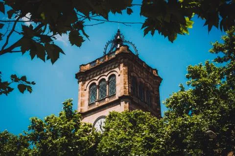 Clock tower of the University of Barcelona through the foliage Stock Photos