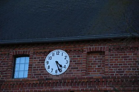 Clock on the wall of the building with red brick Stock Photos