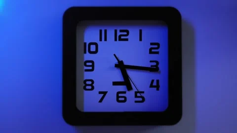 The clock on the wall synchronized with a flickering blue and red light in Stock Footage 322105812
