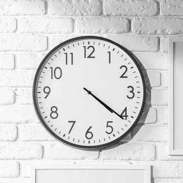 Clock on a white brick wall shows time in a simple, clear design Stock Photos