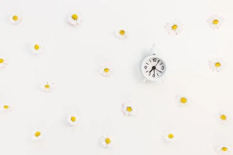 Clock on white with spring flowers background. Spring forward, daylight saving Stock Photos