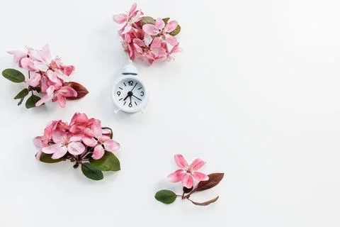 Clock on white with spring flowers background. Spring forward, daylight saving Stock Photos