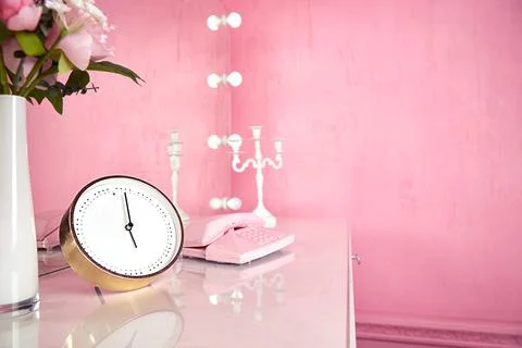 Clocks and interior items on the table in the pink room of a young woman or girl Stock Photos