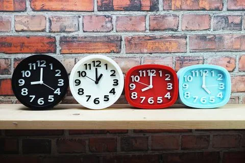 Clocks with time zone of different country on wooden shelves and brick wall b Foto stock