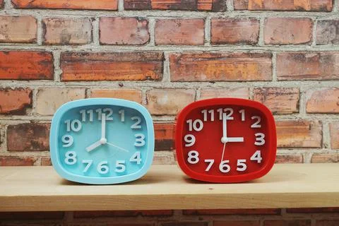 Clocks with time zone of different country on wooden shelves and brick wall b Foto stock
