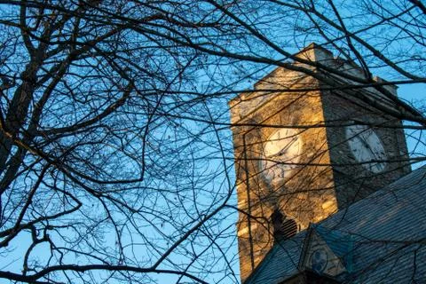 A clocktower bathed in glowing orange sunlight Stock Photos