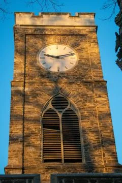 A clocktower bathed in glowing orange sunlight Stock Photos