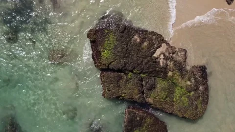 A clockwise aerial zenith shot of a massive rock formation on a pristine, Vidéo 282883579